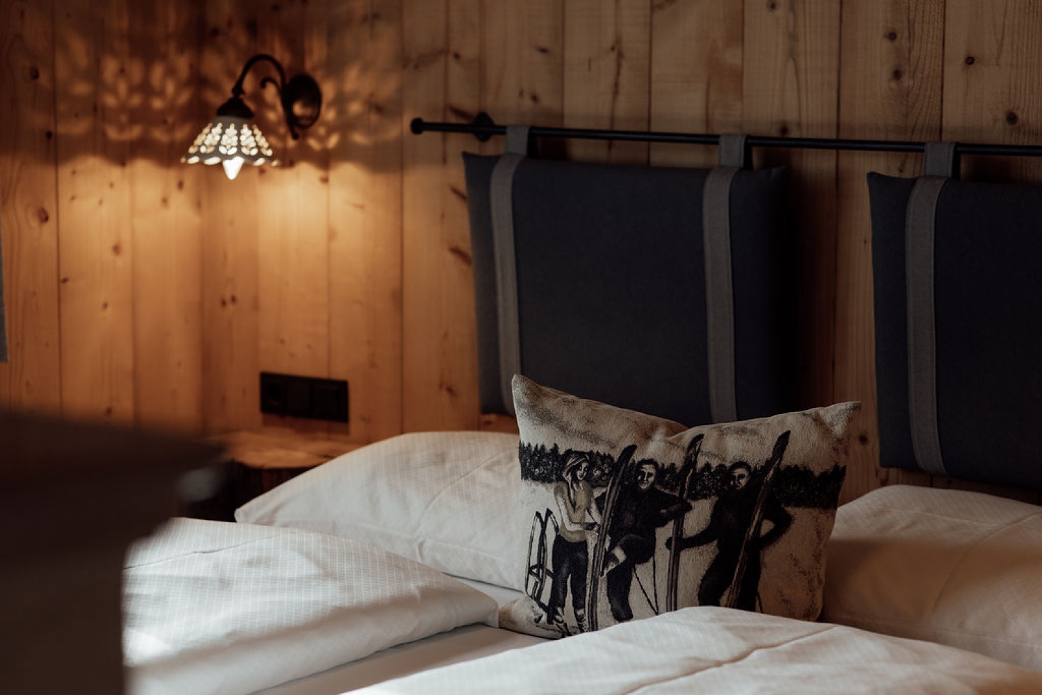 Detailansicht von Bett, Polstern und Holzelementen in der 60 Square Lodge.