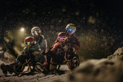 Bild: Family enjoying tobogganing on a snowy natural sled run in St. Anton am Arlberg